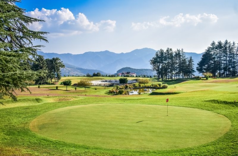 Golfplatz mit Clubhaus und Berge im Hintergrund