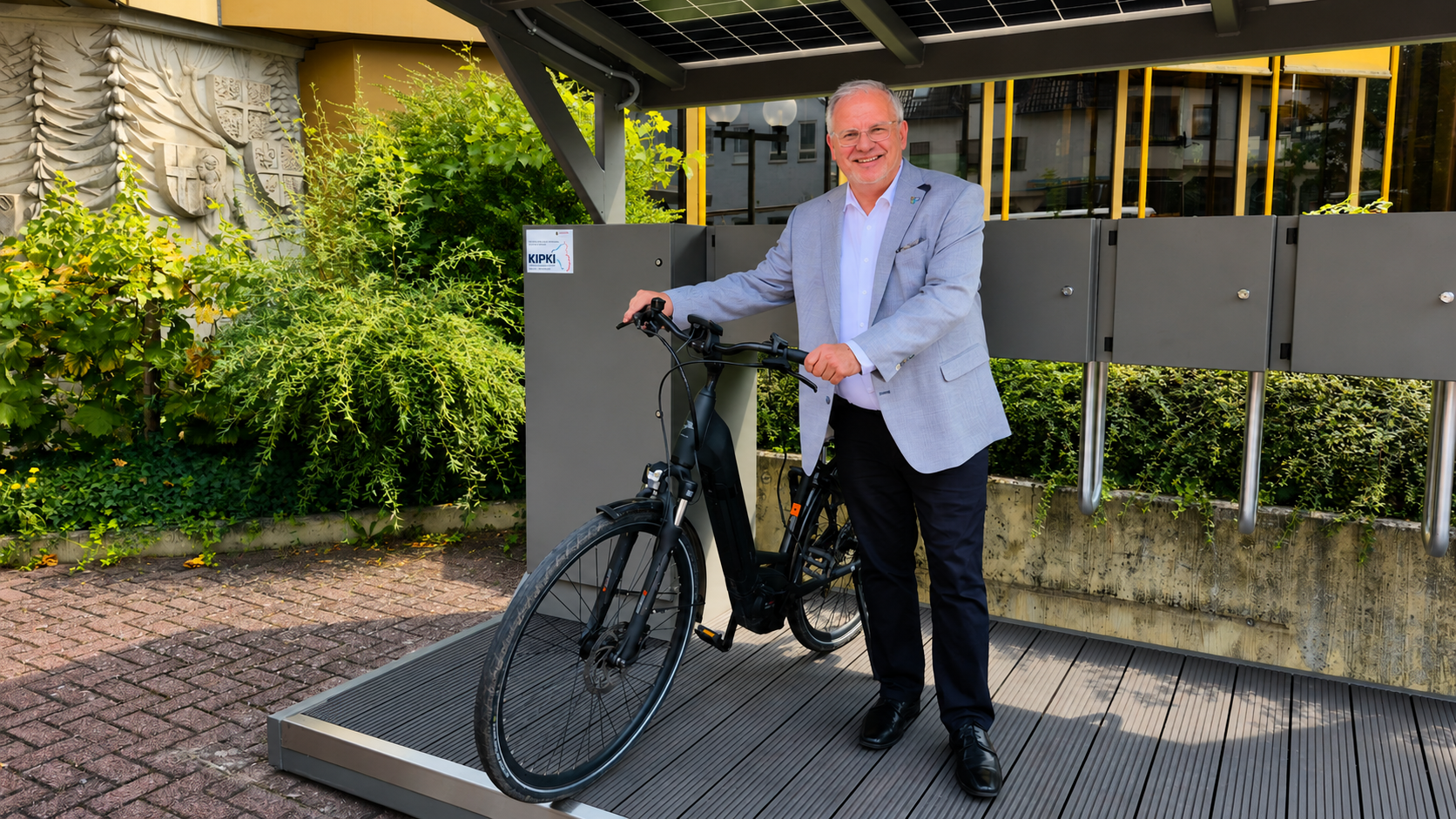 Landrat Hans-Ulrich Ihlenfeld an der neuen E-Bike-Ladestation mit Fahrrad in Bad Dürkheim